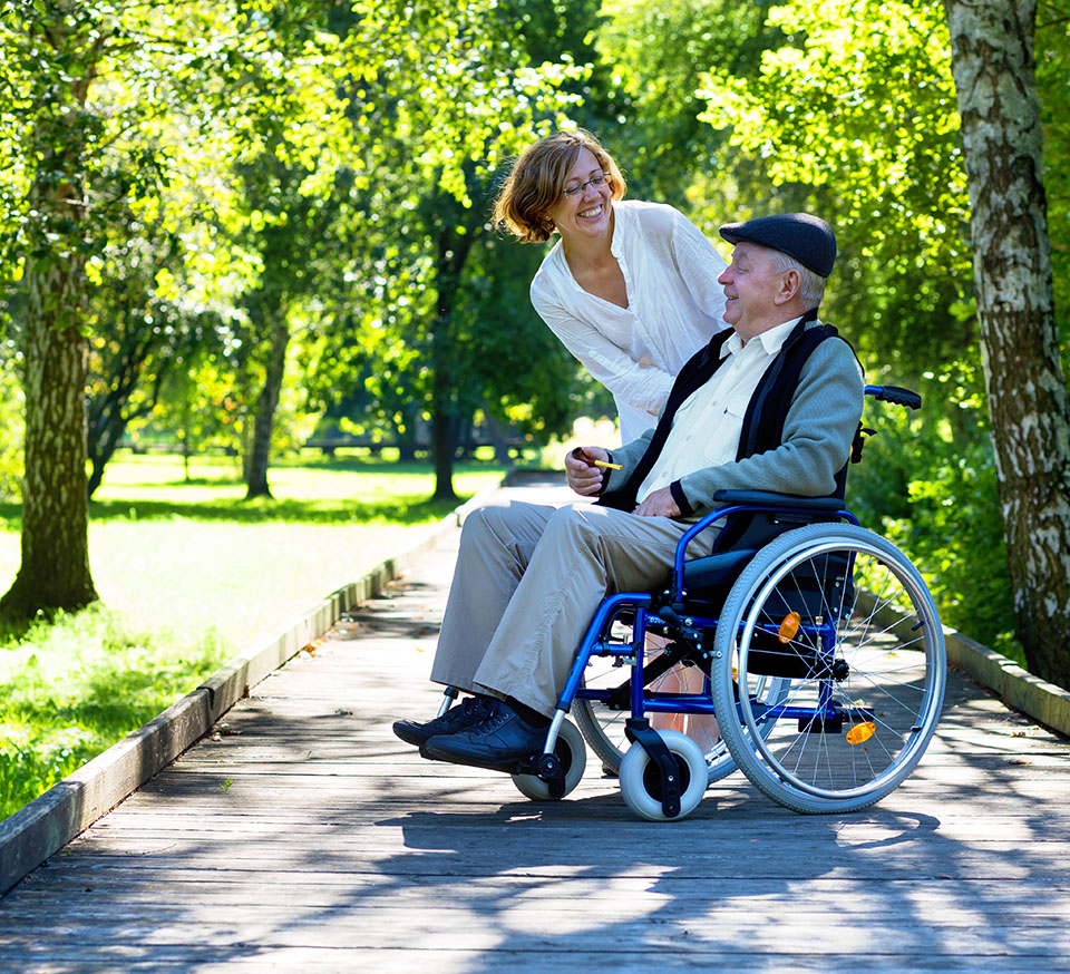 old man on wheelchair and young woman in the park