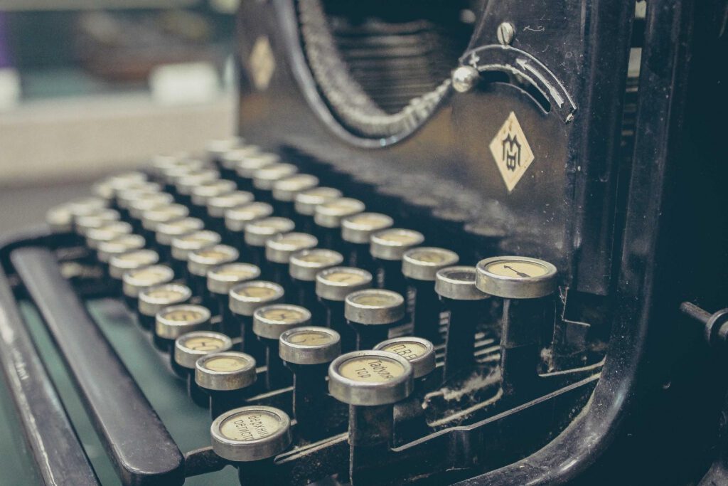 A vintage black typewriter with brass keys and handle.