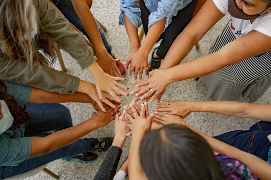 A group of diverse individuals holding hands in a circle, forming a unified group.