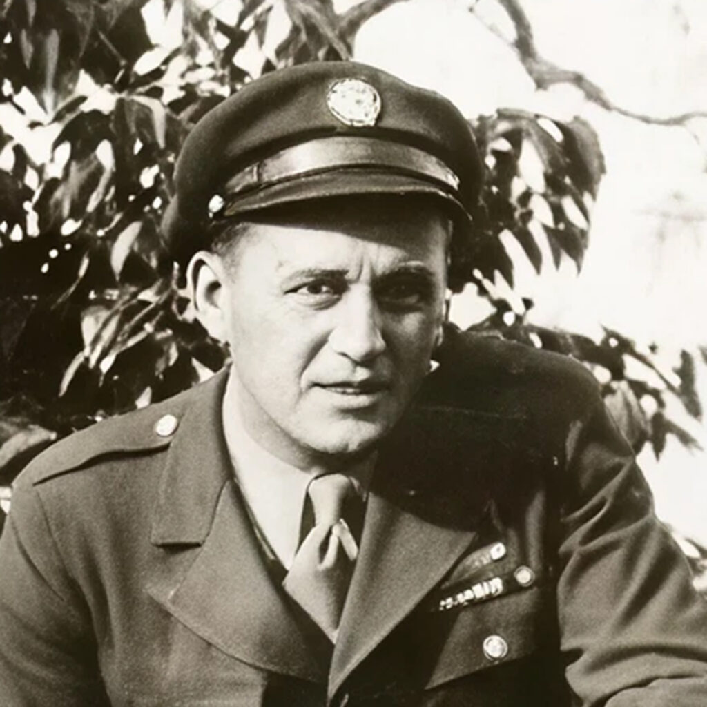 The image shows a person in military attire. The individual is wearing an old-style uniform with badges and a cap with a crest on the front. The photo appears to be an older black and white photograph, as indicated by its quality and graininess.