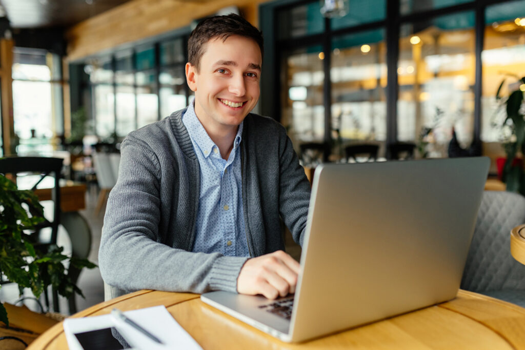 A man working on laptop at table in restaurant setting.