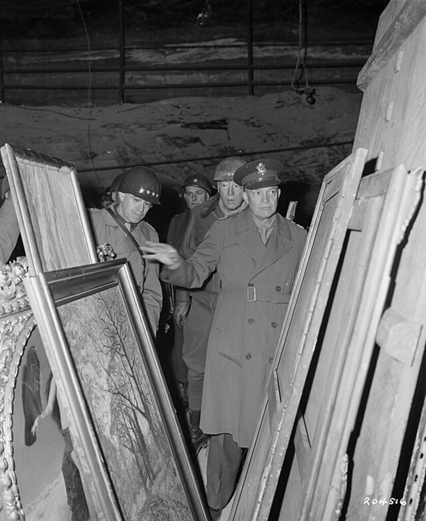 Soldiers examining old paintings in an underground bunker. Dwight D. Eisenhower is at the front of the group.