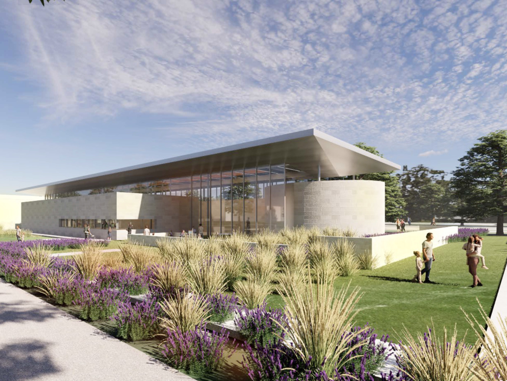 A large, modern building with a glass frontage set in a landscaped outdoor area during daylight hours.