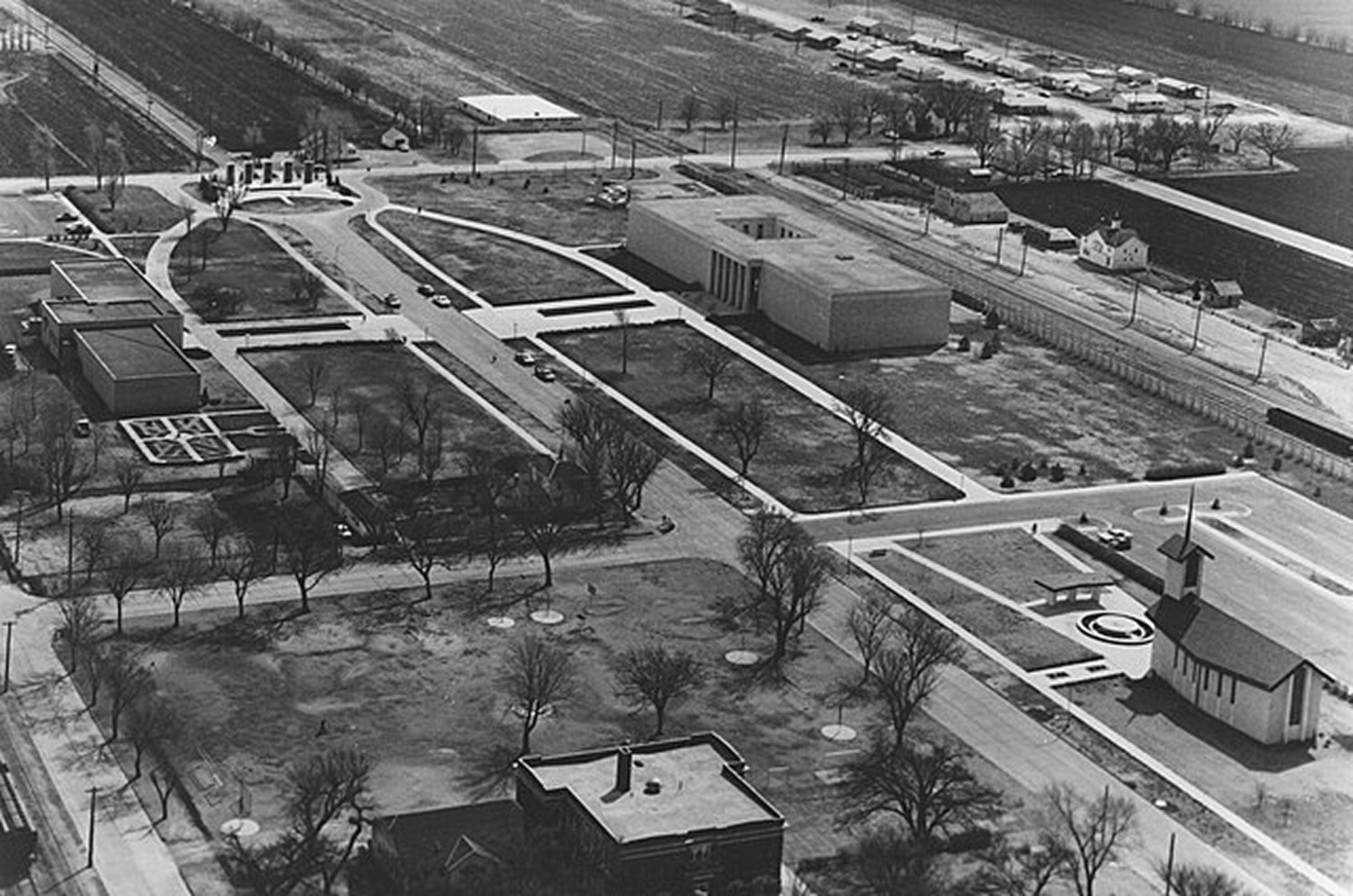 Large aerial view of an open industrial area featuring empty buildings and parking lots, with no visible pedestrians.