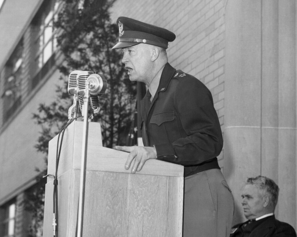 Dwight D. Eisenhower in military uniform speaking at a podium.