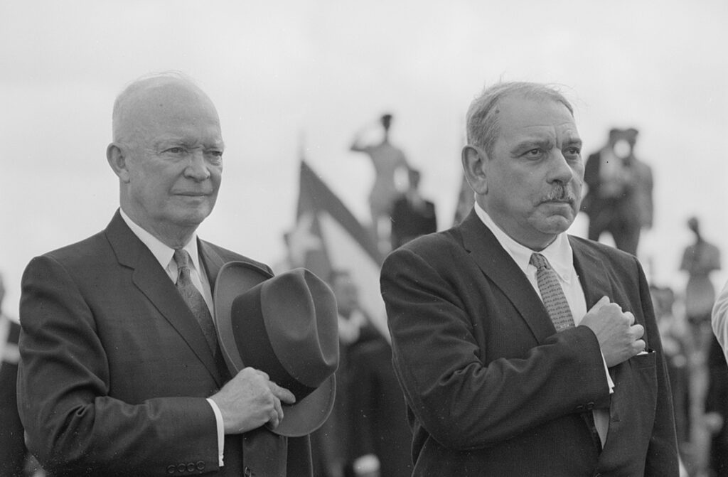 This photograph shows U.S. President Dwight D. Eisenhower and Puerto Rican Governor Luis Muñoz Marín standing together looking at something out of frame.