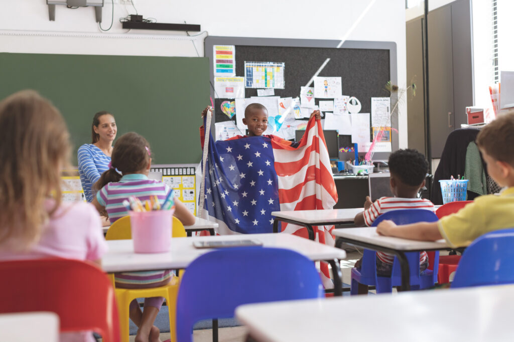 A classroom scene with a student holding an American Flag up for the rest of his class.
