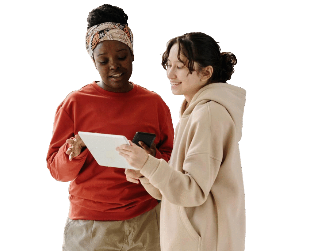 Two individuals examining a tablet. They are both indoors, and one of them has their hair pulled back in a bun.