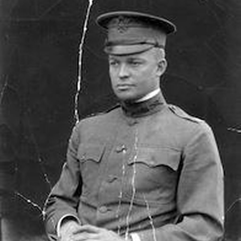 A man in military uniform stands confidently, gazing slightly to the side.