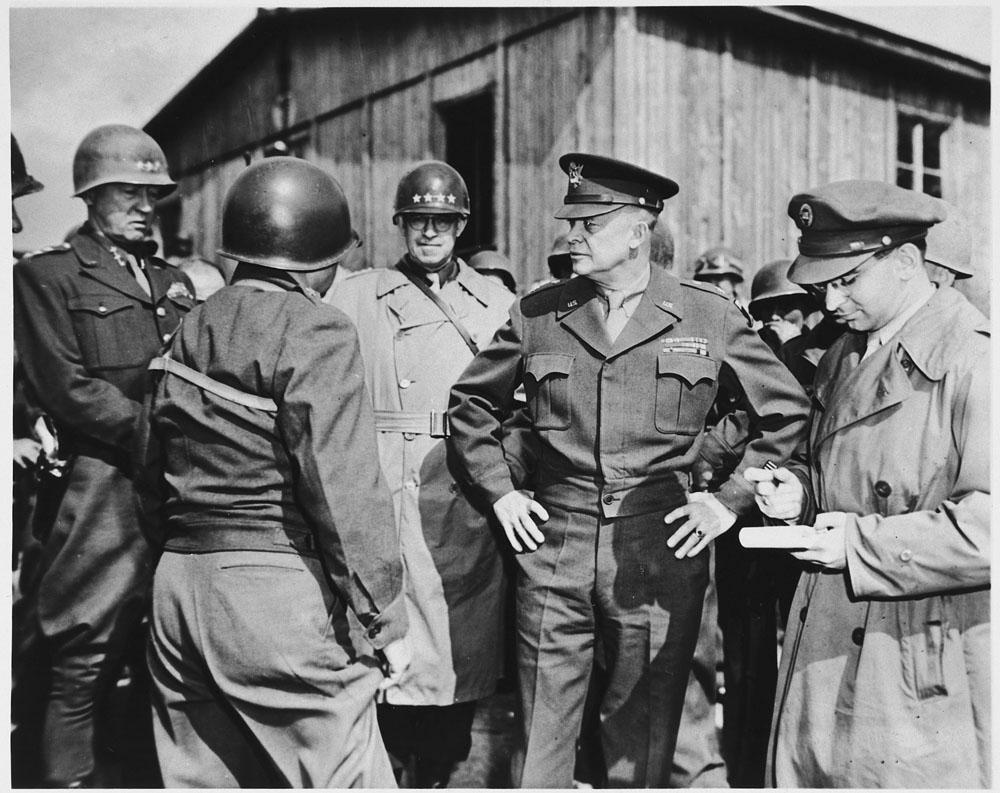 Three military officers inspecting a wartime camp.