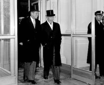 Two men in suits walking together outside a government building.