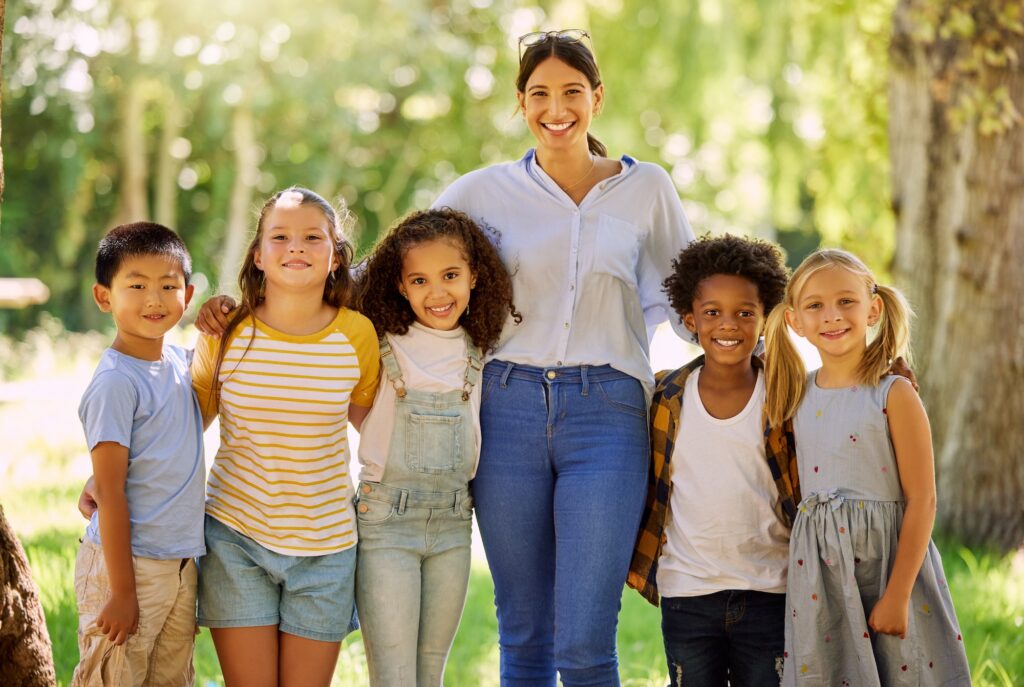 A woman and children standing in a park. They all appear to be posing for a photo.
