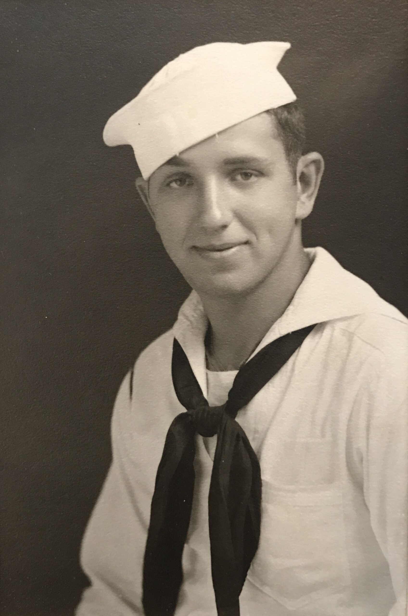 Young sailor wearing a white U.S. Navy uniform and cap.