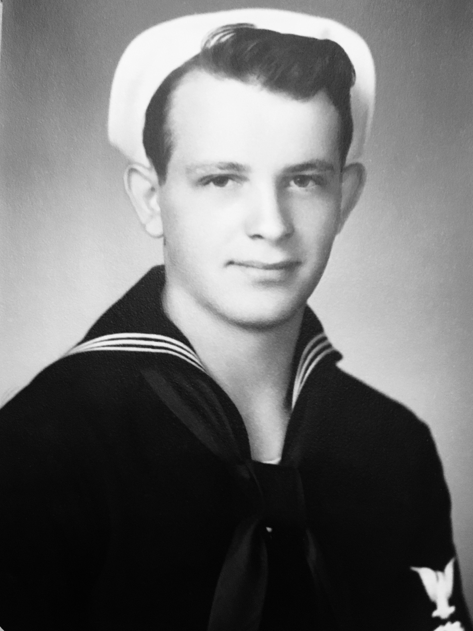Young sailor wearing a dark U.S. Navy uniform in a formal portrait.