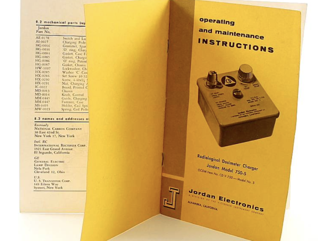 Civil defense dosimeter instruction manual opened beside a yellow handbook.