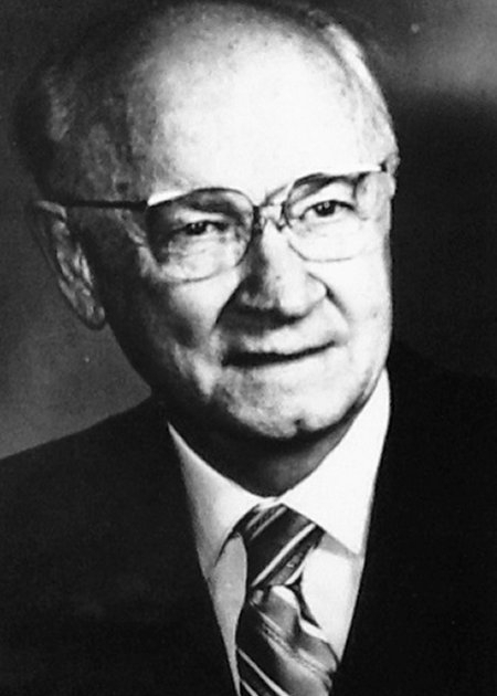 An elderly man in glasses and suit jacket, posing for a portrait. He appears content and composed.