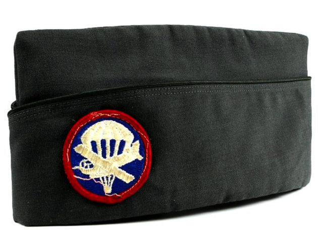 Dark military garrison cap with a circular paraglider patch.