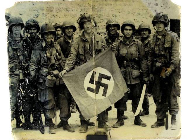 American paratroopers posing with a captured Nazi flag.