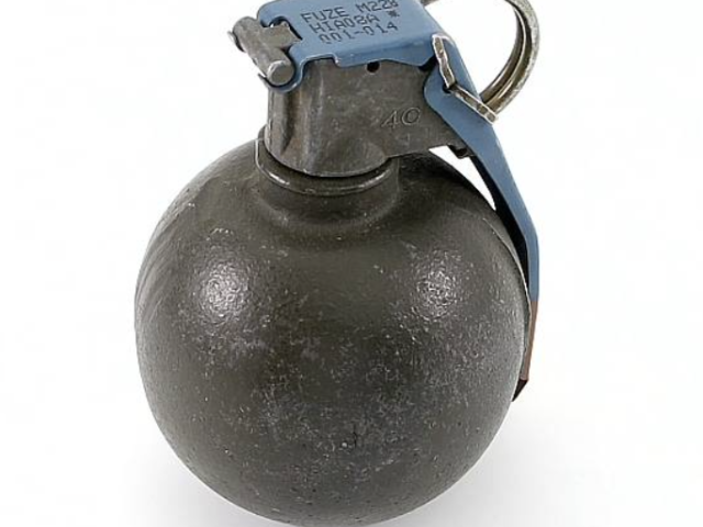 Round military grenade with a safety lever and metal pull ring.