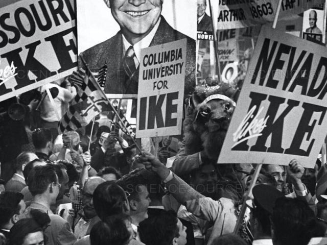 Republican National Convention delegates hold Eisenhower campaign signs in a crowded arena.