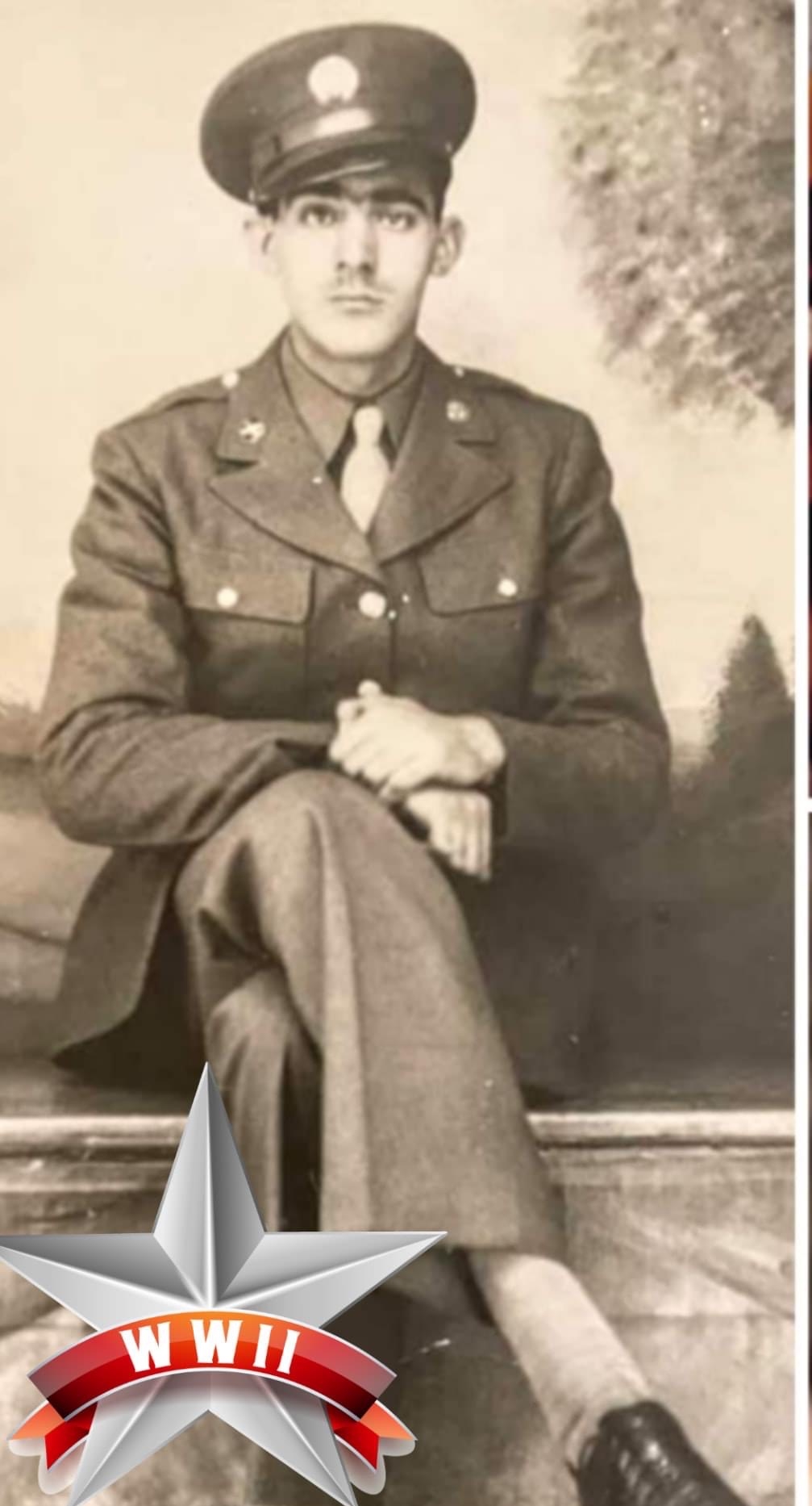 The image shows an old photograph of a military man in uniform, seated with his legs crossed on what appears to be a bench or ledge.