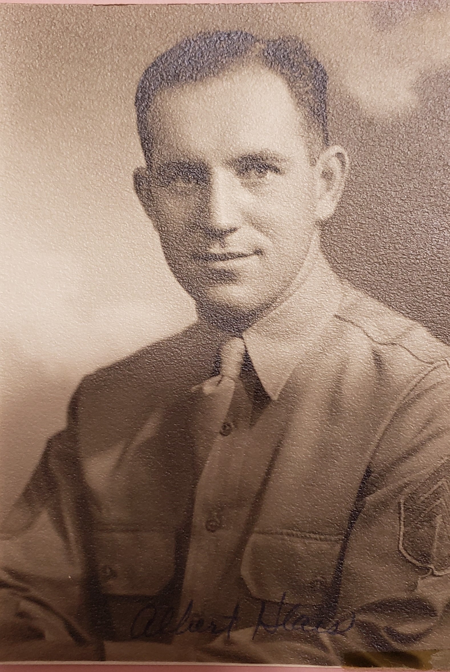 The image is a black-and-white photograph of a man in military attire. He has short hair and appears to be posing for the picture.