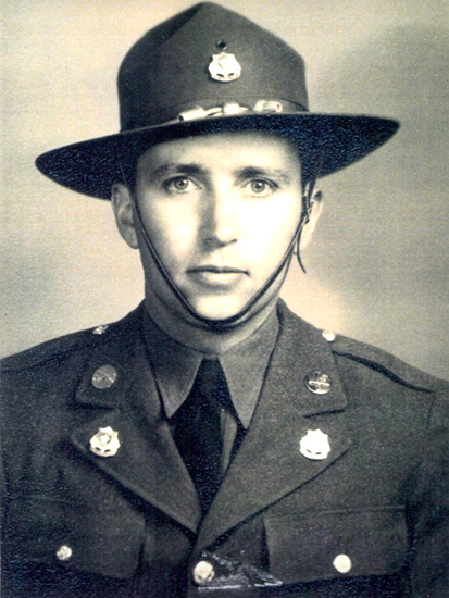 A military man in uniform, wearing a tie and military hat.