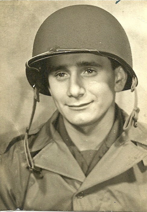 A man in military uniform smiling, wearing helmet with chin strap.