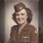 A woman in military uniform wearing a tie, posing for portrait.