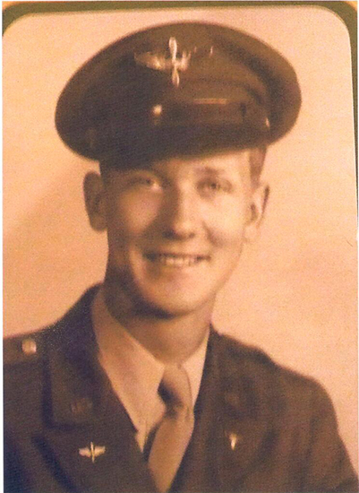 Smiling serviceman wearing a military uniform and peaked cap.