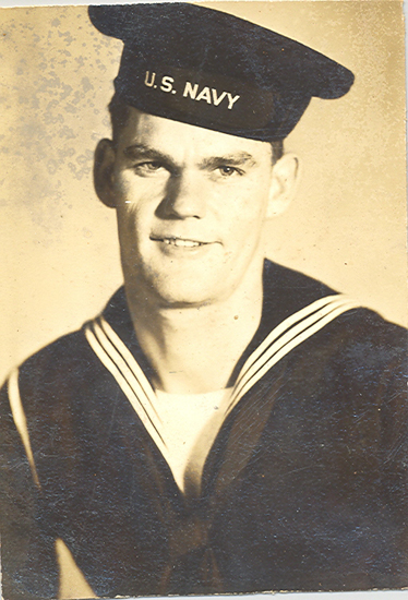 Lawrence Ashton wearing a U.S. Navy uniform and white sailor cap.