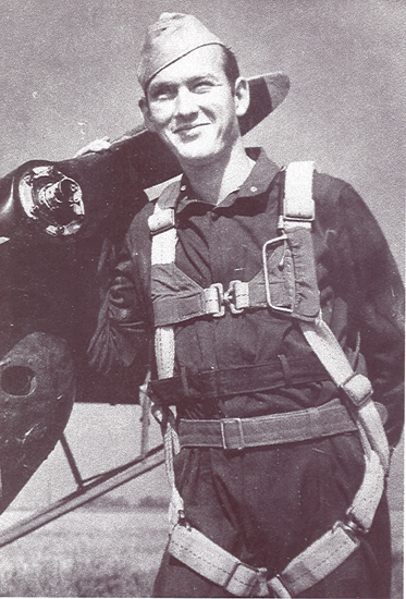 Serviceman wearing military flight gear and a parachute harness.