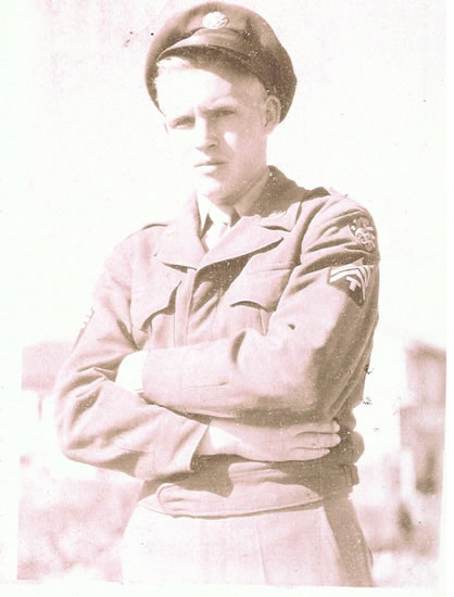 Serviceman standing with arms crossed in a military uniform.