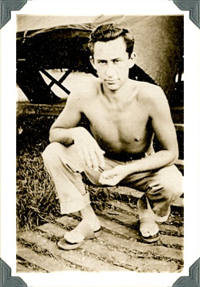 Shirtless young man crouching down outdoors in a black-and-white portrait.