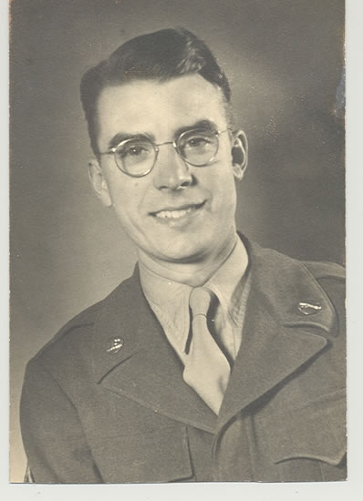 A portrait of a man in military uniform. He is smiling at the camera, wearing glasses with neatly groomed hair.