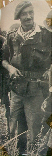 An old black and white photograph of a man in uniform standing outdoors.