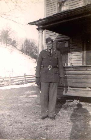 Erving Delbert Clevenger standing outside a wooden building in military uniform.