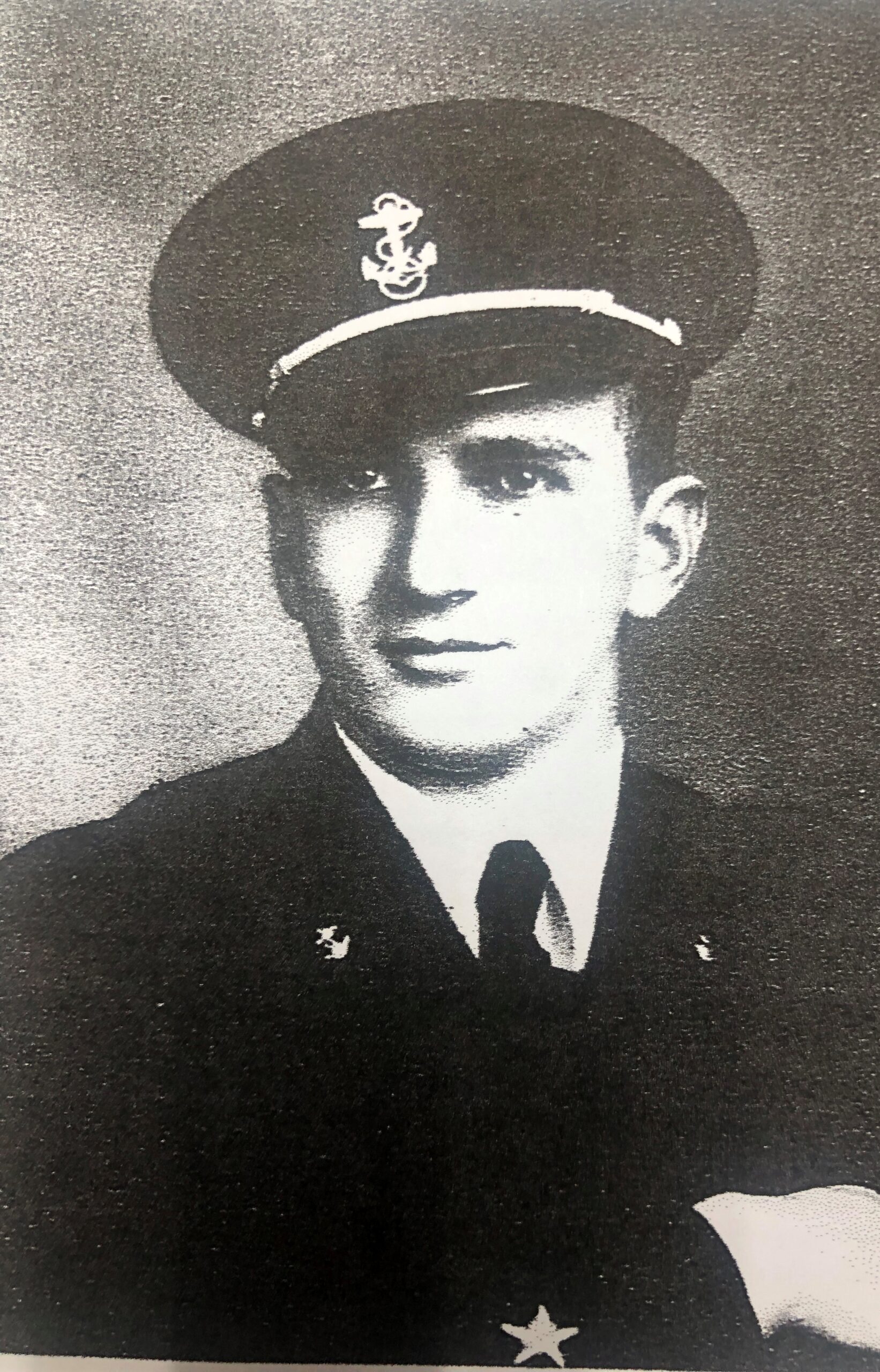 A black-and-white image of a man in military uniform. He has a cap with an insignia on it, and is looking at the camera.