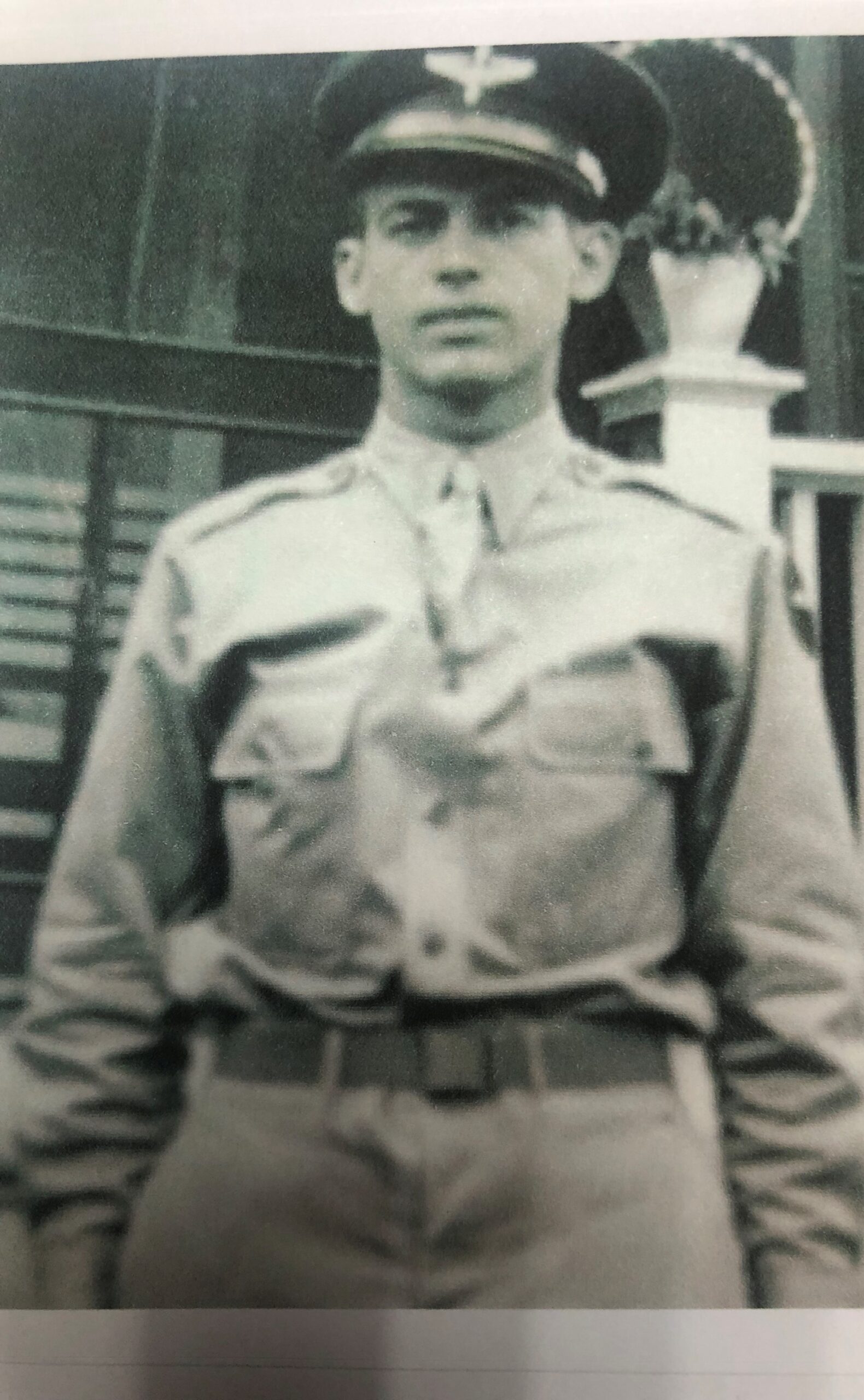 A black and white historical photo of a uniformed military man standing in front of a building with a pillar.