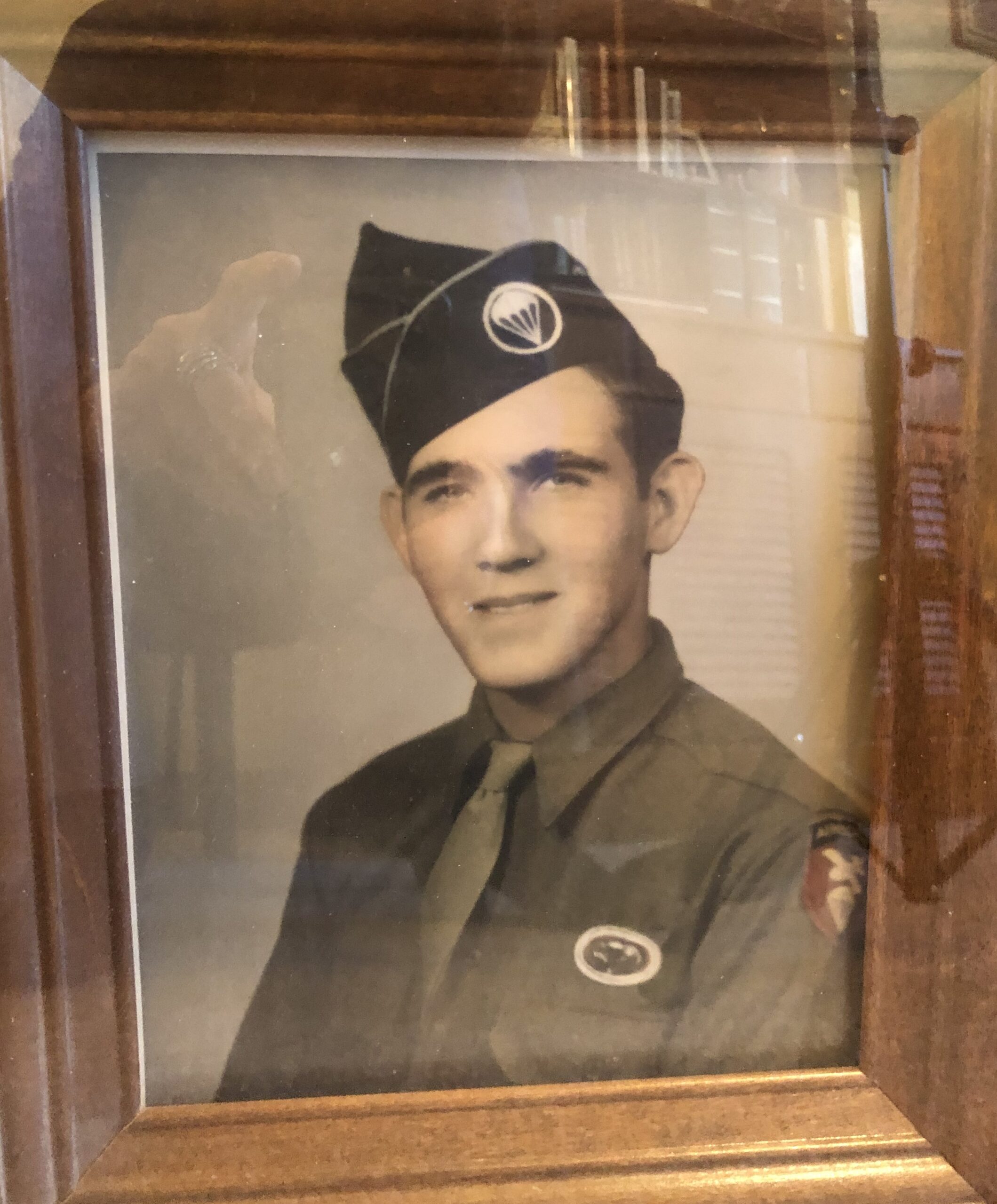 An older photo of an old man in military uniform. He is wearing a tie and has a medal pinned to his chest. The photo appears to be framed. The frame is dark with a light interior, highlighting the picture within.
