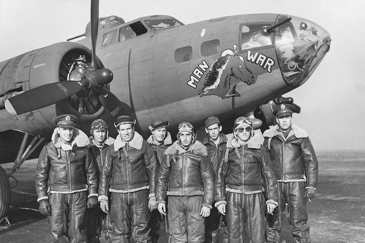 Aircrew posing in front of a military aircraft marked “War.”