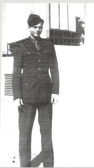 Old black-and-white photograph of a soldier standing in front of a building.