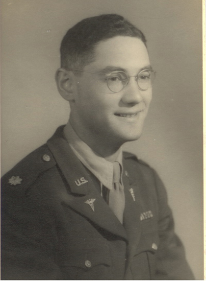An old photograph of a man in military uniform, wearing glasses and smiling at the camera.