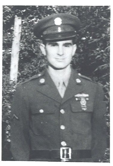 Man in military uniform, standing outdoors for a black-and-white portrait photograph.