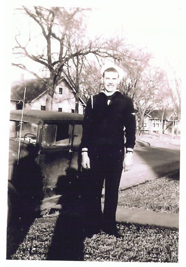 Elmer Vern Holt standing beside a vehicle in a dark naval uniform.