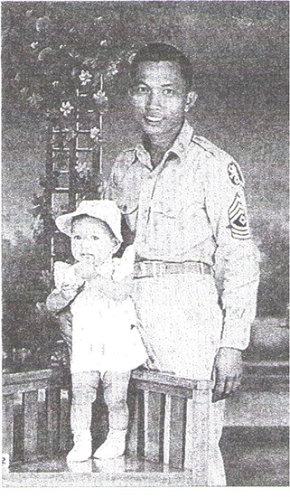 Juan R. Fabia standing outdoors in uniform beside a young child.