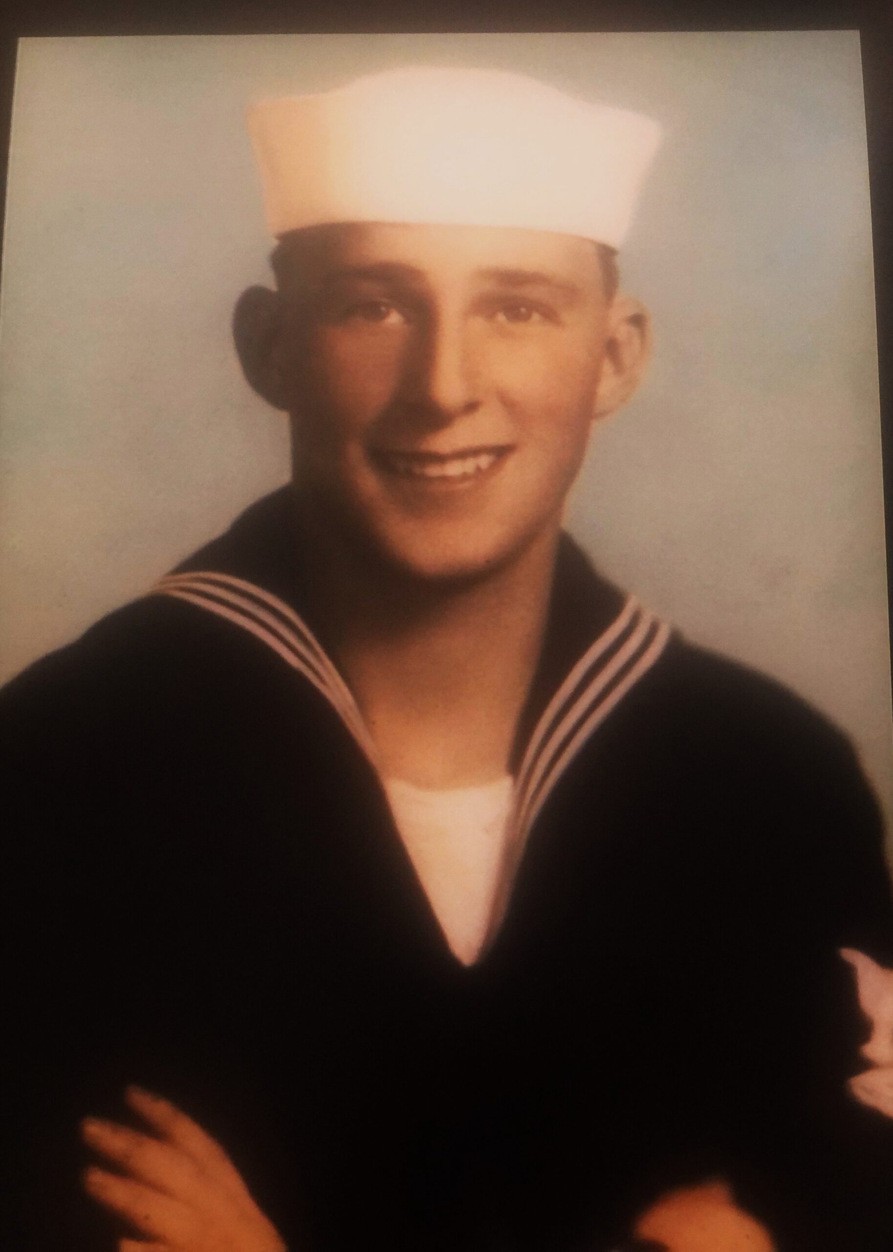 Smiling young sailor wearing a dark U.S. Navy uniform.