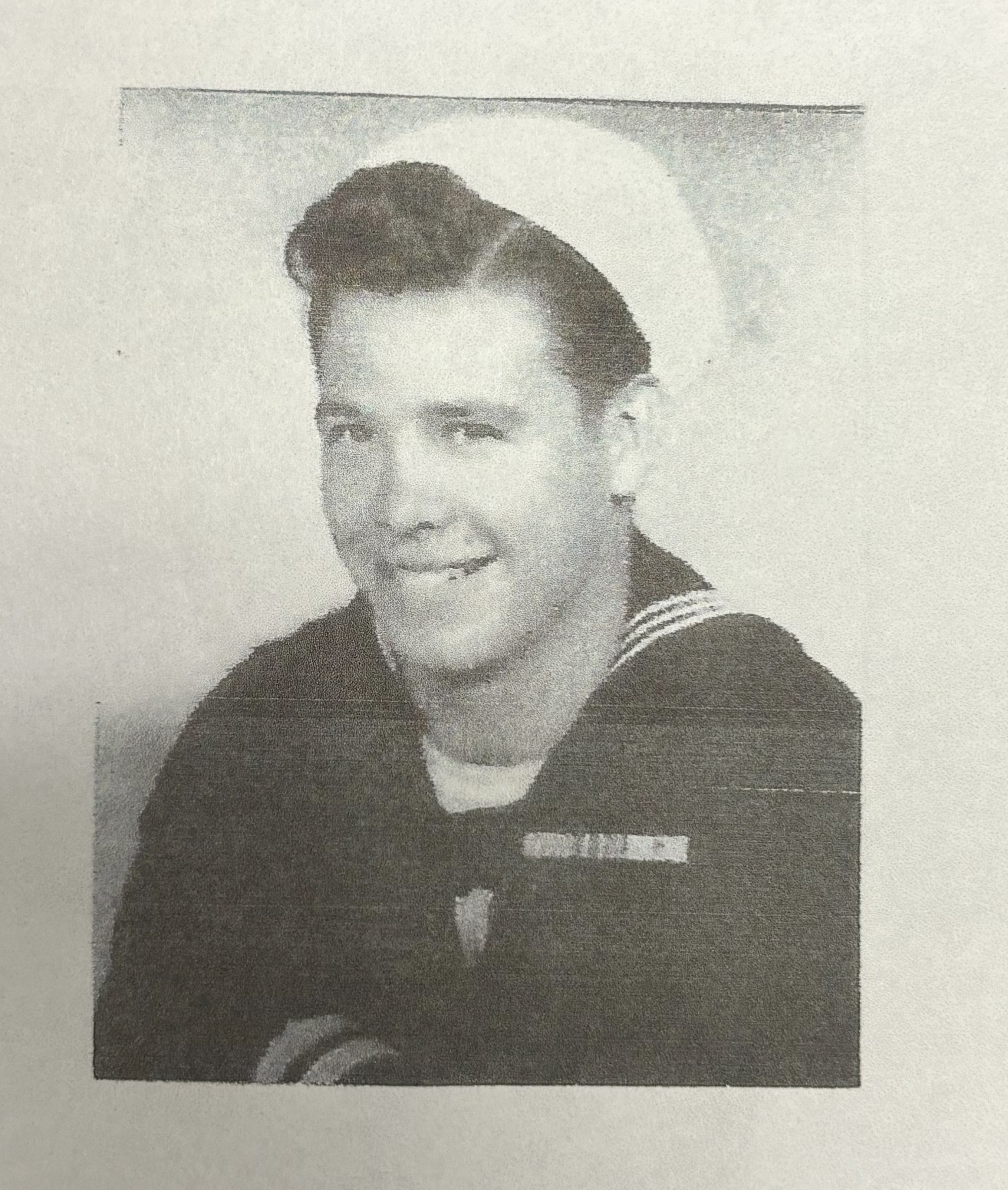 Smiling sailor wearing a dark U.S. Navy uniform.