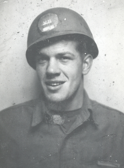 Smiling soldier wearing a military helmet in a close-up portrait.