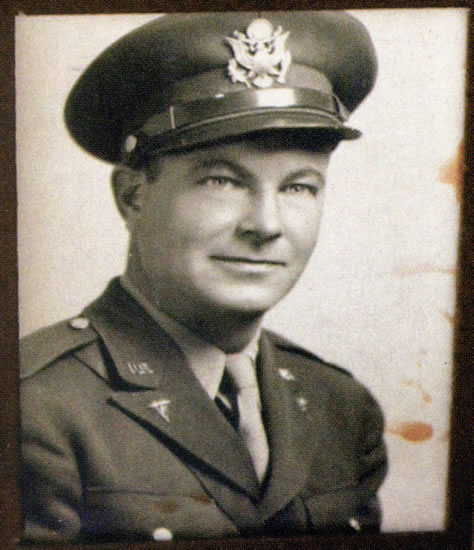 Military officer wearing a dress uniform and peaked cap.